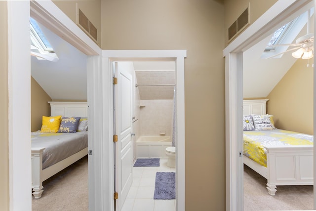 bedroom featuring light tile patterned floors, vaulted ceiling with skylight, ensuite bathroom, and visible vents
