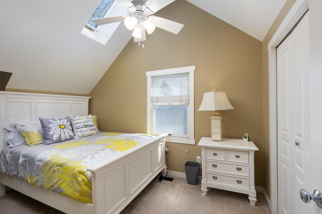bedroom with a closet, carpet floors, baseboards, lofted ceiling with skylight, and ceiling fan