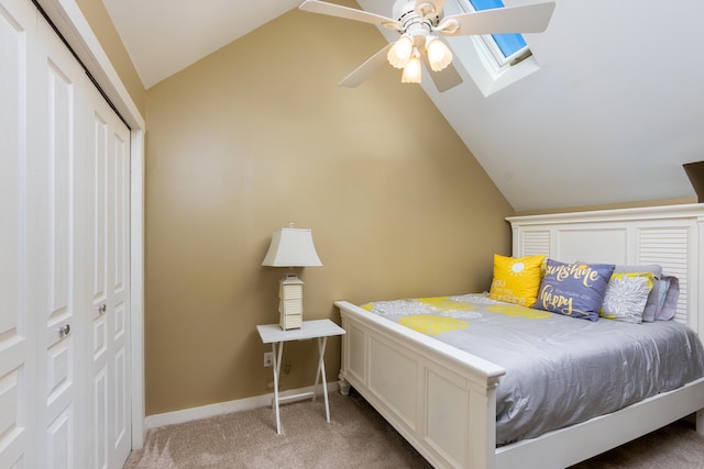 carpeted bedroom featuring baseboards, ceiling fan, a closet, and lofted ceiling with skylight