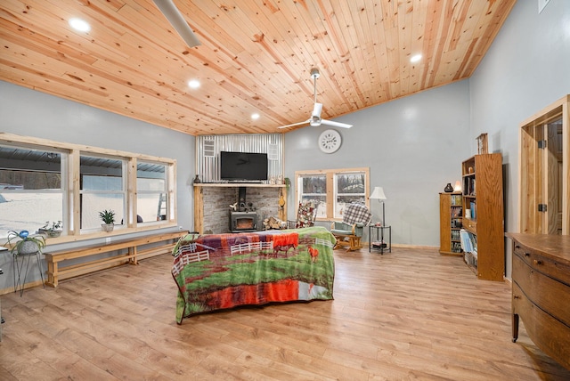 living room featuring ceiling fan, light wood-type flooring, a wood stove, and wooden ceiling