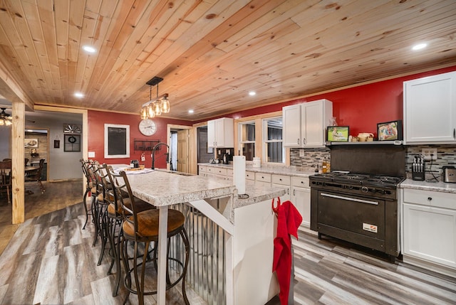 kitchen featuring white cabinetry, hanging light fixtures, and luxury range