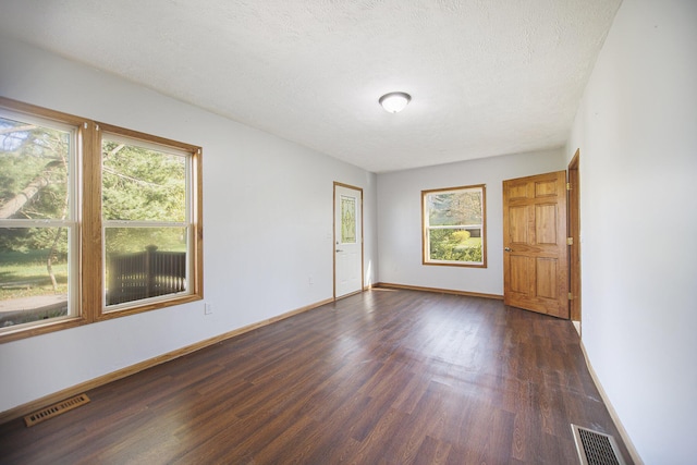 unfurnished room with dark hardwood / wood-style flooring and a textured ceiling