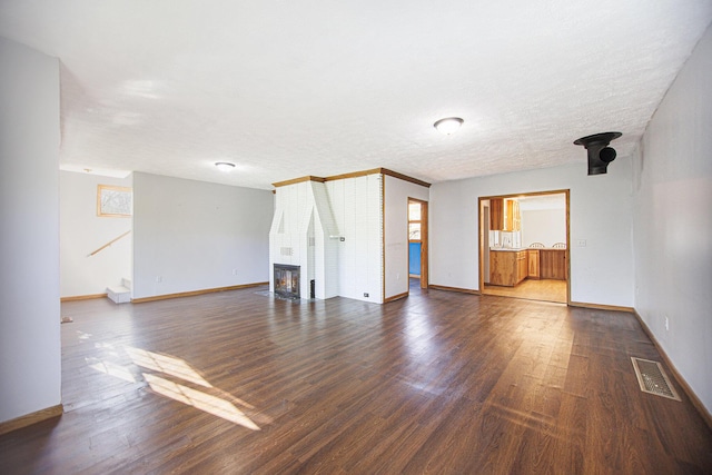 unfurnished living room with a textured ceiling, a fireplace, and dark wood-type flooring