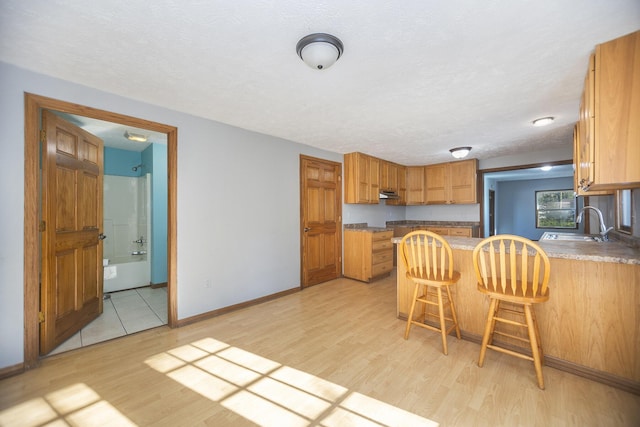 kitchen featuring a kitchen bar, kitchen peninsula, sink, and light hardwood / wood-style flooring