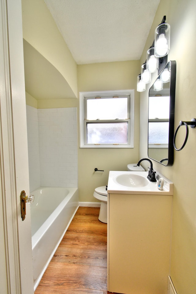 bathroom with vanity, a textured ceiling, a bath, wood-type flooring, and toilet