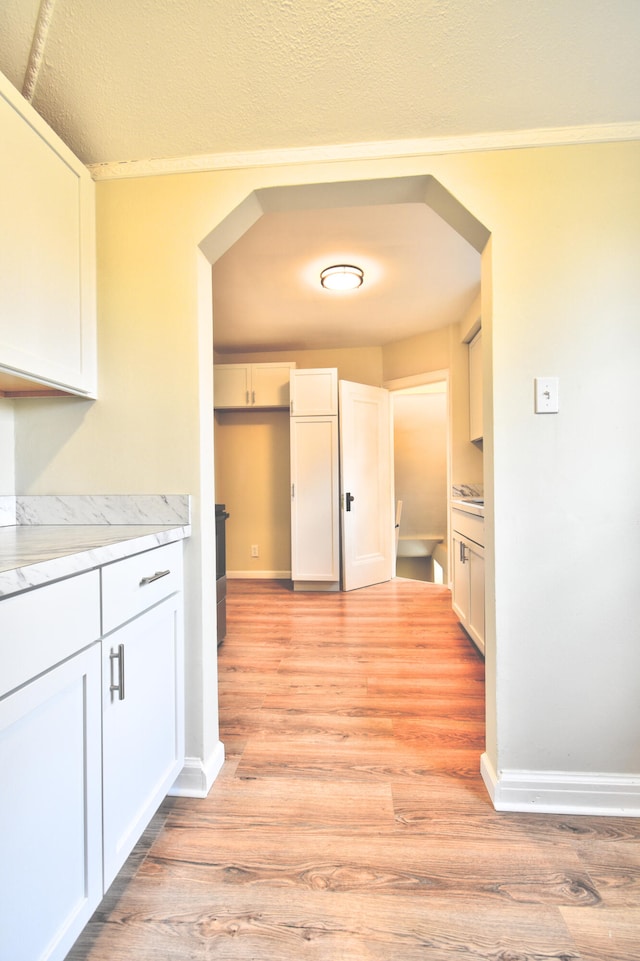 hallway with a textured ceiling and light wood-type flooring