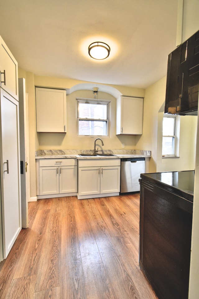 kitchen featuring light wood-type flooring, stainless steel dishwasher, a healthy amount of sunlight, sink, and white cabinetry