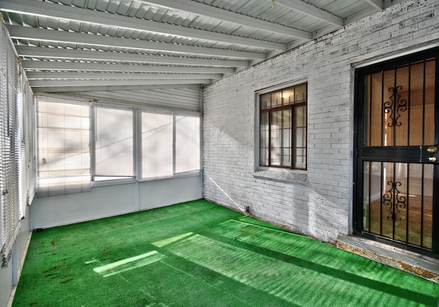 unfurnished sunroom featuring lofted ceiling with beams