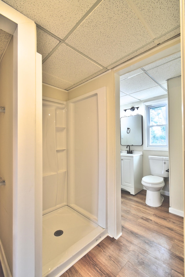 bathroom featuring a shower, toilet, a paneled ceiling, vanity, and hardwood / wood-style flooring