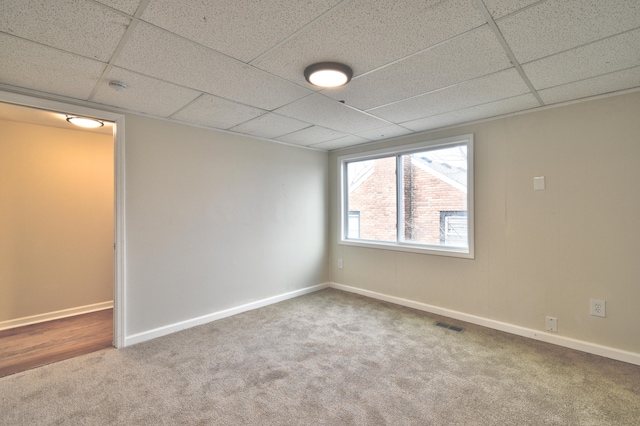 unfurnished room featuring carpet and a drop ceiling