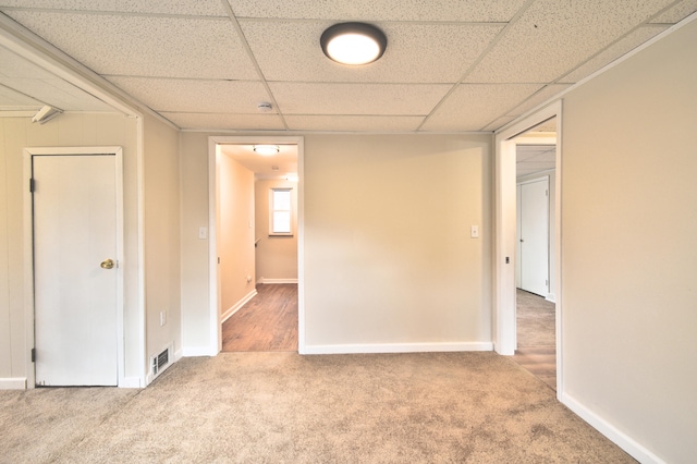 carpeted empty room featuring a drop ceiling