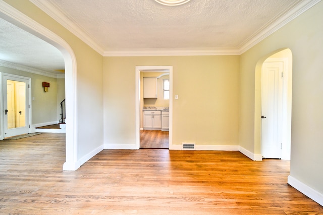 unfurnished room with crown molding, a textured ceiling, and light wood-type flooring