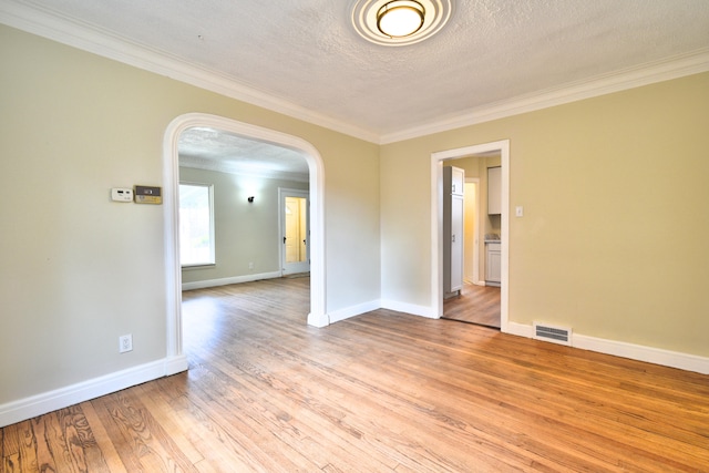 empty room featuring a textured ceiling, light hardwood / wood-style floors, and crown molding