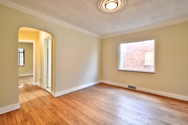 spare room with light hardwood / wood-style floors, a textured ceiling, and ornamental molding