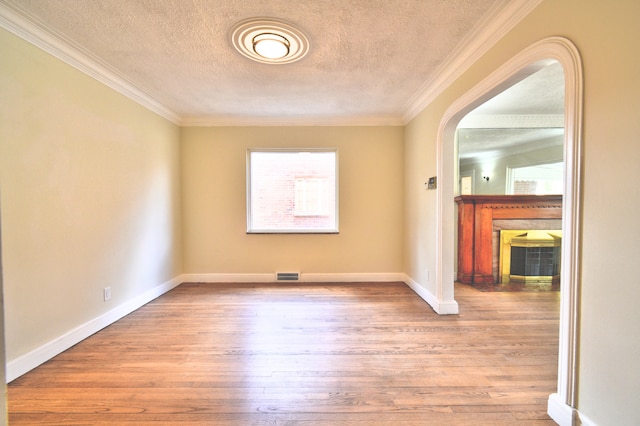 unfurnished room featuring a textured ceiling, light hardwood / wood-style flooring, and ornamental molding