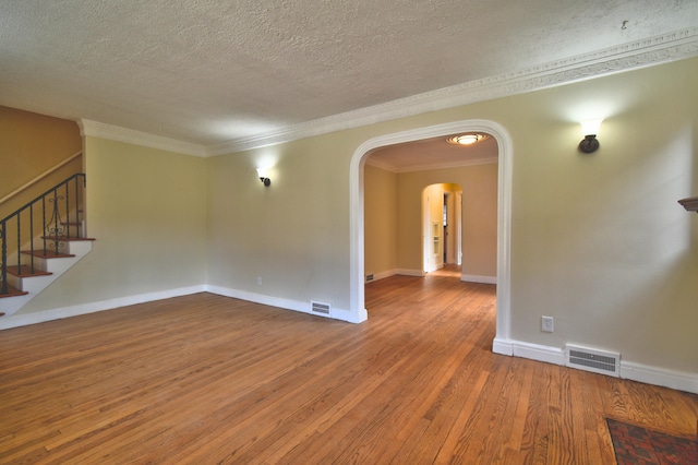 spare room featuring a textured ceiling, hardwood / wood-style flooring, and ornamental molding