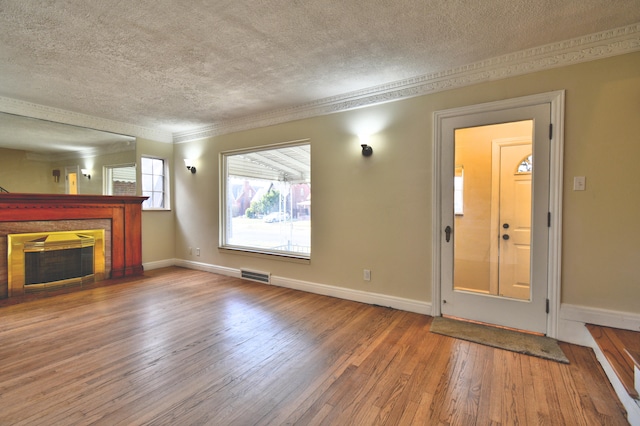 unfurnished living room with crown molding, wood-type flooring, and a textured ceiling