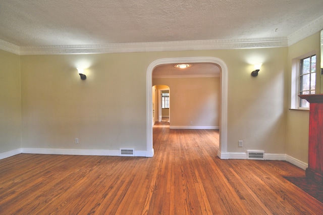 spare room with a textured ceiling, dark hardwood / wood-style flooring, and crown molding