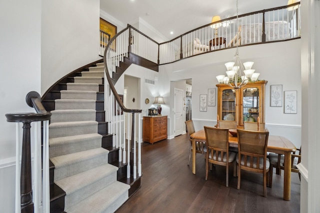 dining space with a notable chandelier, a towering ceiling, and dark wood-type flooring