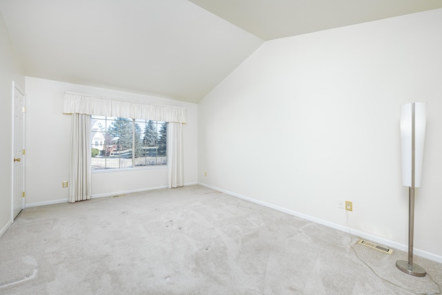 carpeted spare room with vaulted ceiling