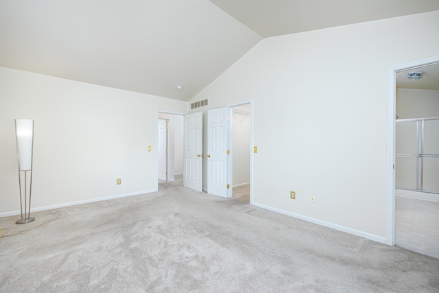 unfurnished bedroom featuring a spacious closet, a closet, light colored carpet, and vaulted ceiling