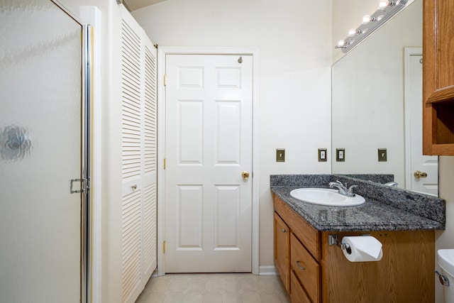 bathroom with tile patterned floors, vanity, a shower with shower door, and toilet