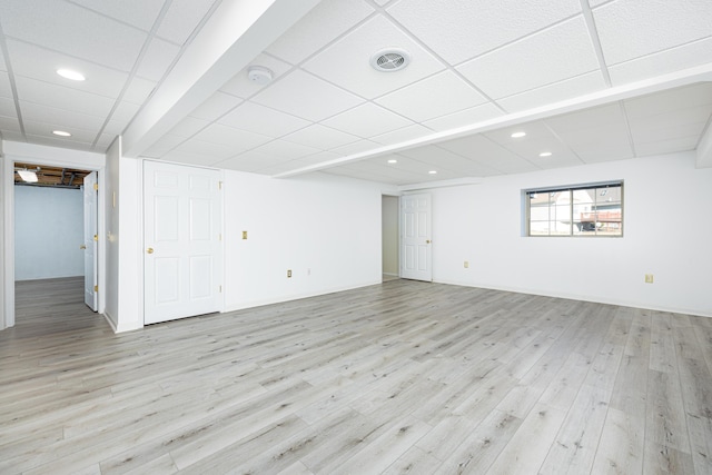 basement with a drop ceiling and light wood-type flooring