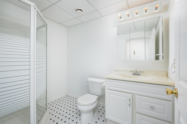 bathroom with a drop ceiling, toilet, a shower with shower door, and vanity