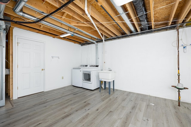 clothes washing area with washing machine and clothes dryer, hardwood / wood-style floors, and sink