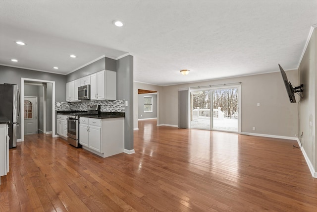 kitchen with stainless steel appliances, white cabinets, decorative backsplash, and light wood-type flooring