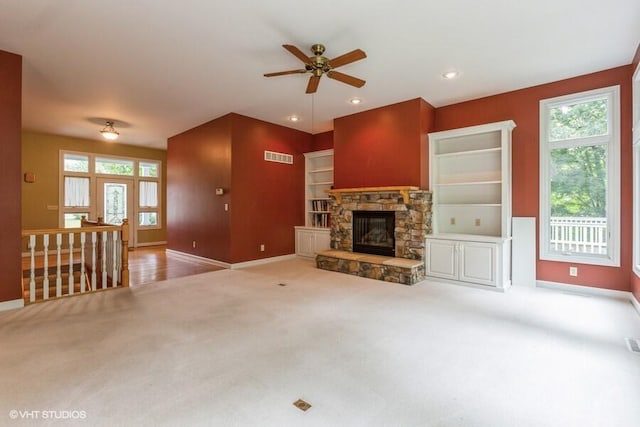 unfurnished living room with ceiling fan, a fireplace, and light carpet