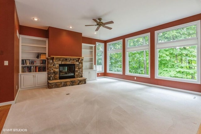 unfurnished living room featuring a fireplace, light carpet, ceiling fan, and built in shelves