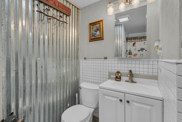 bathroom featuring vanity, tile walls, and toilet