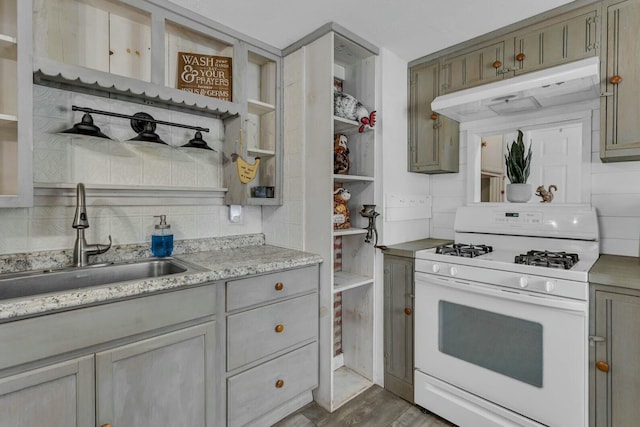 kitchen with light wood-type flooring, tasteful backsplash, gas range gas stove, and sink