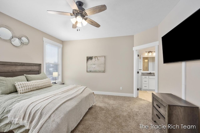 bedroom with ceiling fan, light colored carpet, and ensuite bathroom