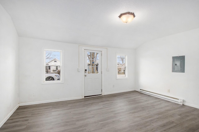 empty room with baseboard heating, electric panel, hardwood / wood-style floors, and lofted ceiling