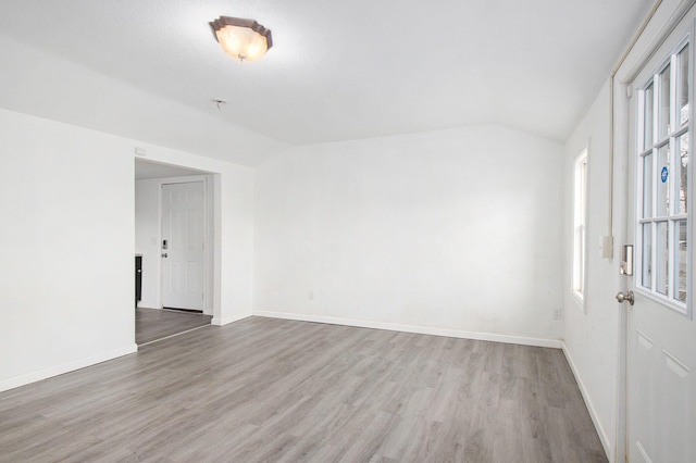 empty room featuring hardwood / wood-style floors, a healthy amount of sunlight, and lofted ceiling