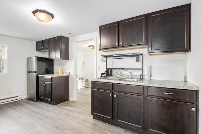 kitchen featuring sink, a baseboard radiator, dark brown cabinets, light hardwood / wood-style floors, and stainless steel refrigerator