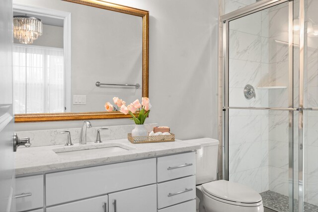 bathroom featuring a shower with door, vanity, an inviting chandelier, and toilet