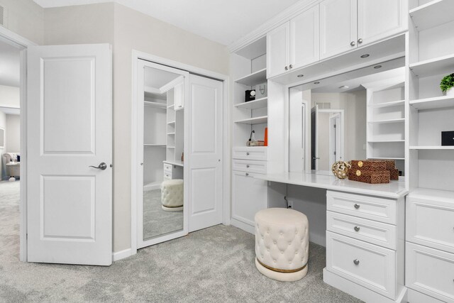 spacious closet featuring light carpet and built in desk