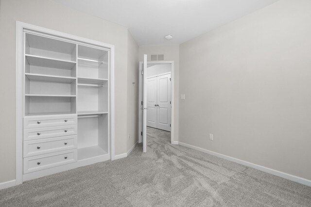 unfurnished bedroom featuring light carpet and a closet