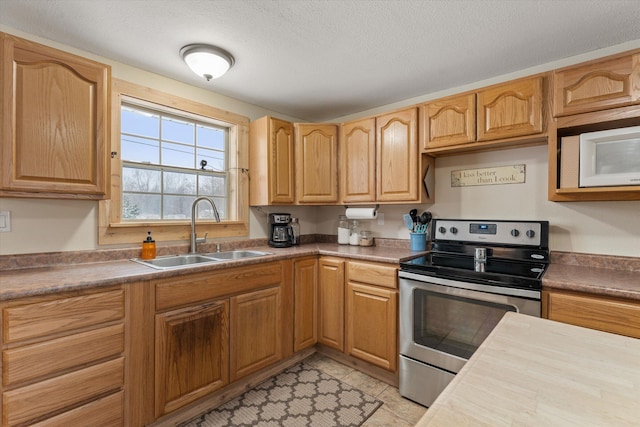 kitchen with sink, stainless steel electric stove, light tile patterned flooring, and a textured ceiling