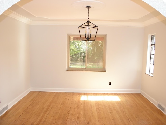 spare room with hardwood / wood-style floors, plenty of natural light, and a chandelier