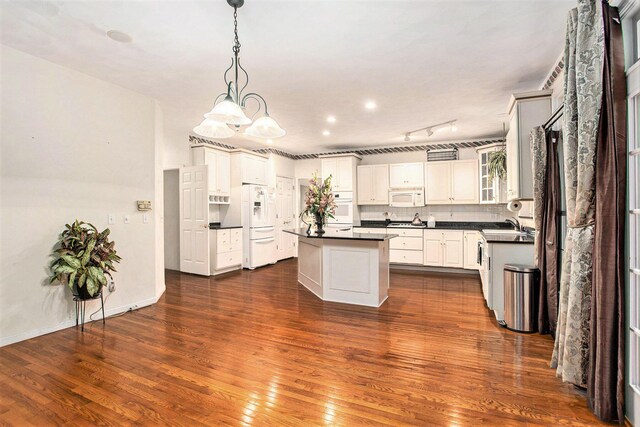 119 Kingsbury Ct, Battle Creek, MI 49015 - kitchen featuring white appliances, dark wood-type flooring, hanging light fixtures, a kitchen island, and white cabinetry