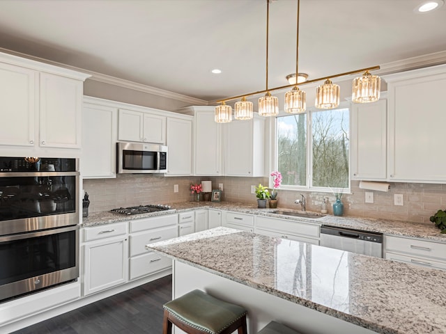 kitchen featuring white cabinets, appliances with stainless steel finishes, a breakfast bar area, and sink