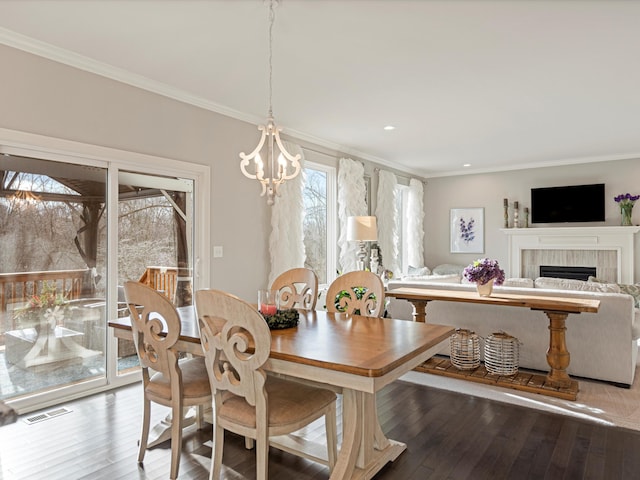 dining area with ornamental molding, a notable chandelier, a healthy amount of sunlight, and wood-type flooring