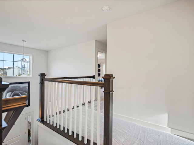 stairway featuring carpet flooring and a chandelier