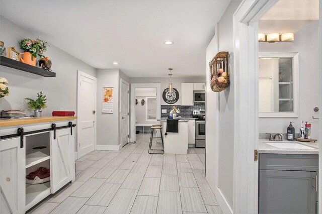 kitchen with pendant lighting, sink, gray cabinets, stainless steel appliances, and tasteful backsplash