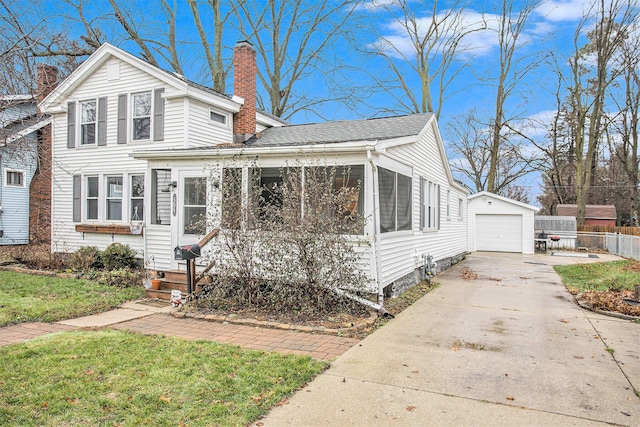 view of front of house featuring an outbuilding, a garage, a sunroom, and a front yard