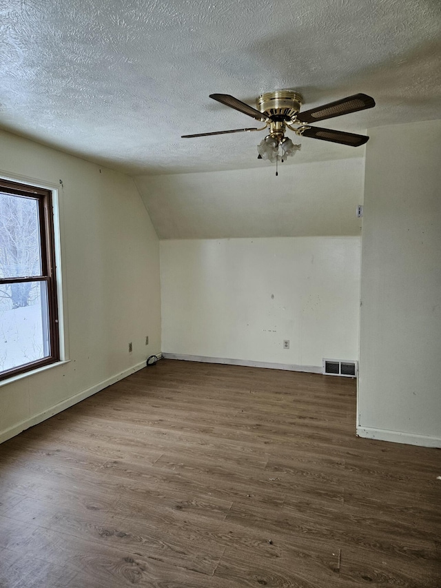 additional living space with vaulted ceiling, ceiling fan, a textured ceiling, and dark hardwood / wood-style floors